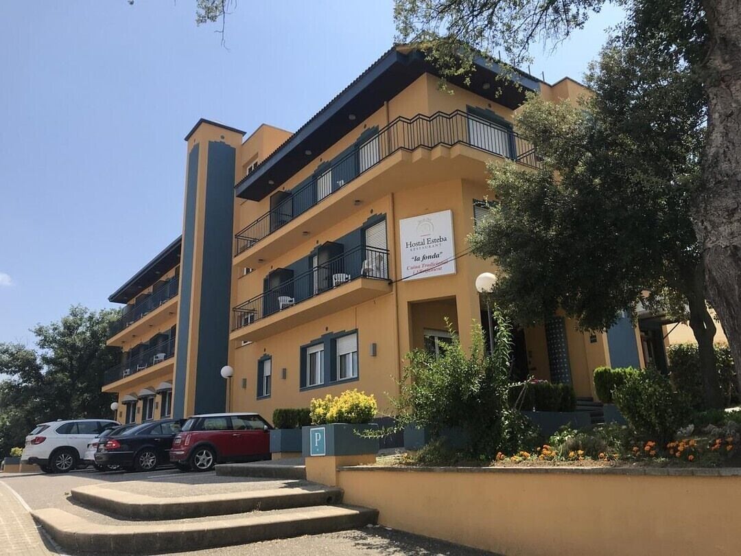 Um hotel com vários andares, varandas, área de estacionamento e uma placa indicando 'Hotel Estrella'.