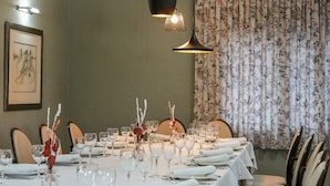 A dining area with tables set for multiple guests, chairs, and hanging pendant lights. - Hostal Esteba (Caldes de Malavella)