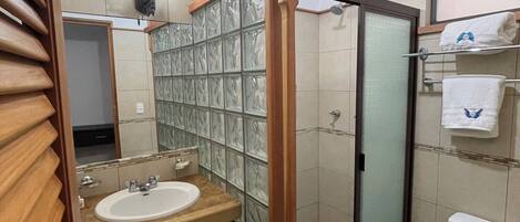 A bathroom with a glass shower enclosure, a sink with a mirror, and a toilet.