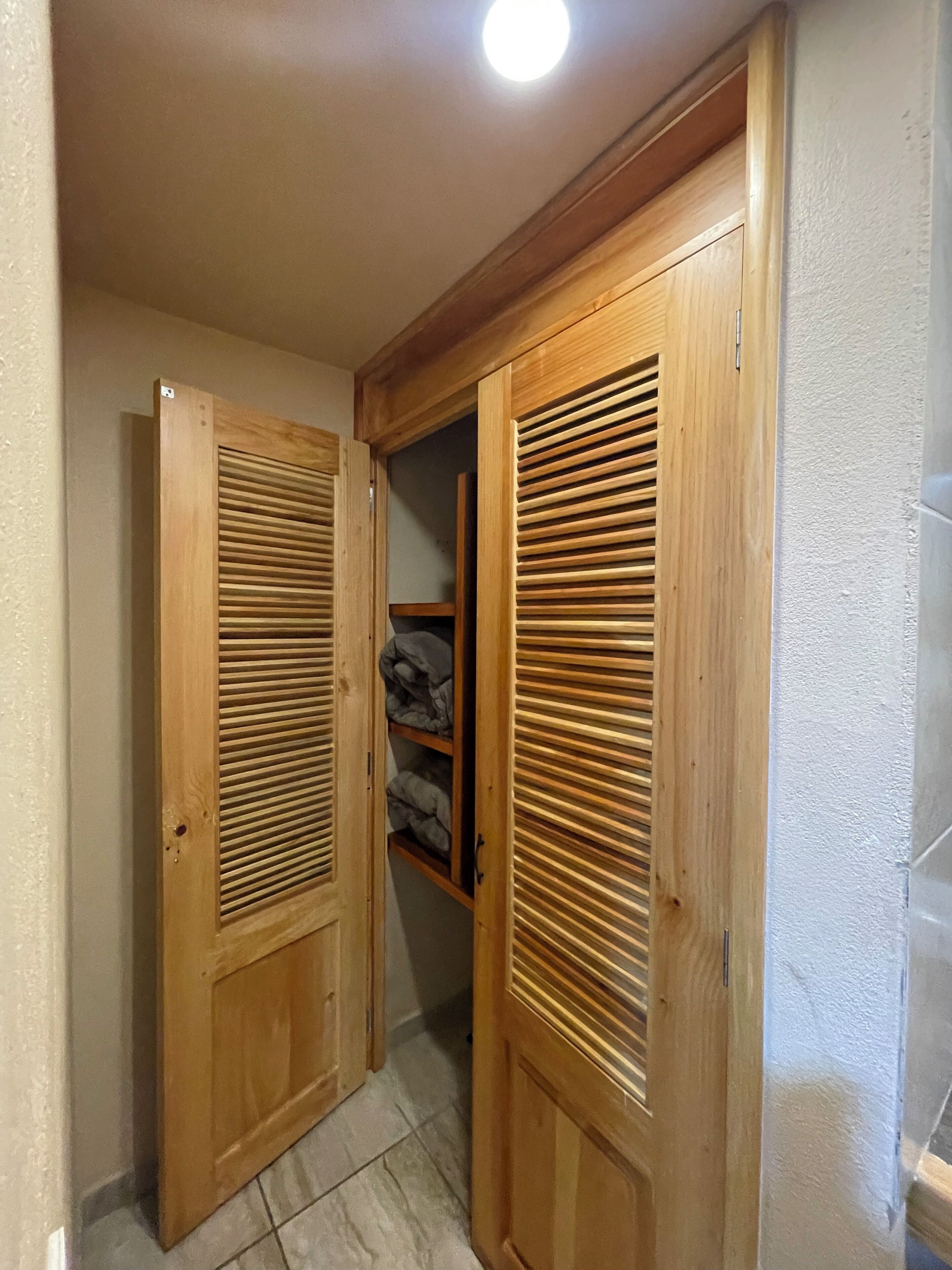 Un pasillo con puertas de madera y suelo de baldosas.