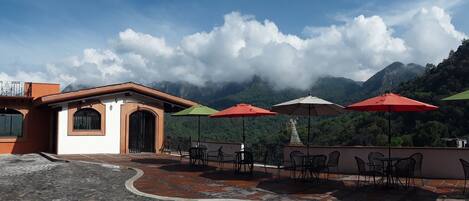 A terrace with outdoor seating and a view of mountains.
