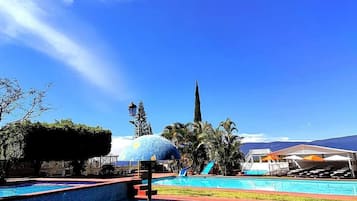 Una piscina al aire libre, sillones reclinables de piscina