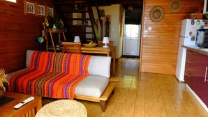 L’intérieur chaleureux d’un chalet avec un canapé, une table à manger en bois et un coin cuisine.