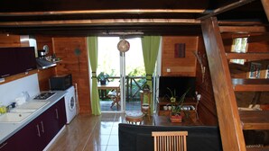Une cuisine compacte avec un coin repas, des murs en bois et une vue à travers une porte vitrée.