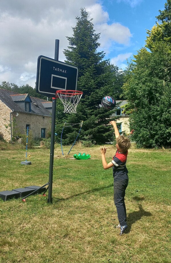 A child playing basketball in a backyard with a hoop labeled "TARMAK."