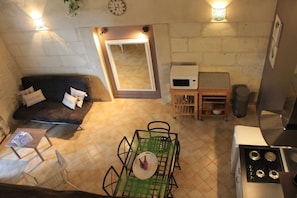 A compact living space with a sofa, a dining table, a microwave, and a stove. - Lodging near Amboise, Chenonceau, Chaumont / Loire (Mosnes)