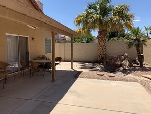 Eine Terrasse mit Tisch und Stühlen, eine Palme und im Hintergrund ein Basketballkorb.