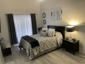 Ein Schlafzimmer mit Bett, Nachttisch, Lampe und Vorhängen.