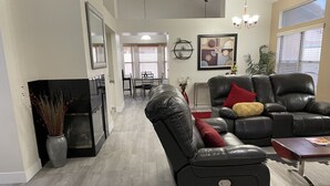 Un salon moderne avec un canapé en cuir, un coin repas et une cheminée.