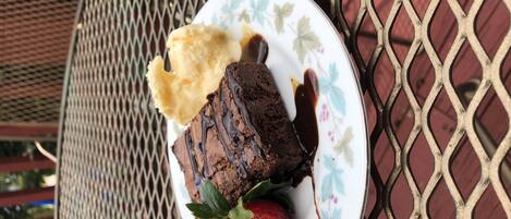 A plate with a dessert consisting of a chocolate cake, a scoop of vanilla ice cream, and a strawberry on a decorative plate.