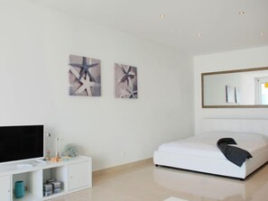 Une chambre moderne comprenant un lit, un téléviseur, une armoire et deux œuvres d’art abstraites accrochées au mur.