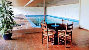 Un espace piscine aménagé avec une table et des chaises, un pot de fleurs et un sol carrelé.