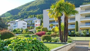 Un hôtel moderne doté d’un toit plat, entouré d’une végétation luxuriante et adossé à une chaîne de montagnes.