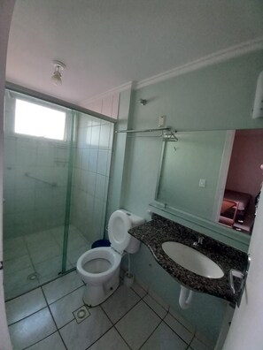 Een badkamer met een douchecabine van glas, een toilet en een wastafel met spiegel erboven.