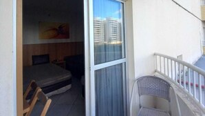 A balcony with a sliding glass door leading to a bedroom with a bed and a chair. - Thermas Place - Férias em Caldas Novas (Caldas Novas)