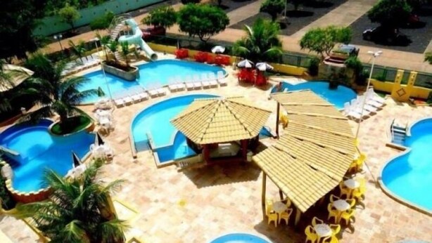 A resort with multiple swimming pools, sun loungers, umbrellas, and a water slide. - Thermas Place - Férias em Caldas Novas (Caldas Novas)