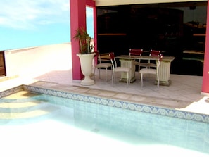 Un espace piscine avec une table et des chaises, une plante en pot et une vue sur le ciel.