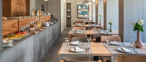 Ein modernes Restaurant mit einer langen Theke, Holzstühlen und Pendelleuchten.
