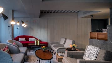 A modern living room with a red sofa, grey armchairs, and a checkered armchair. There are three pendant lights, a coffee table, and a fireplace.