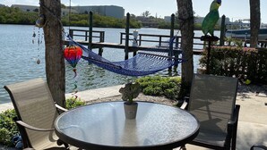 A hammock tied between trees, a round glass table with a potted plant, and a chair.