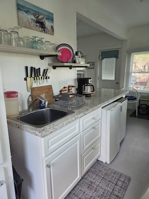 A kitchen with white cabinets, a granite countertop, a coffee maker, and a sink.