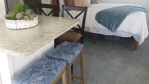 A bedroom with a bed, a bedside table, a chair, and a bench. - Adorable Cottage Townline Lake Paradise. Boat Kayak Fish BBQ Relax Swim. 2 BR  (Lakeview)