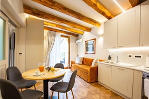 Une cuisine moderne avec des meubles blancs, un plafond en bois et un coin repas comprenant une table et des chaises.