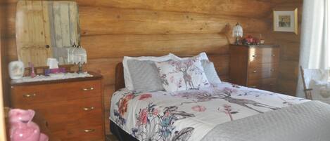 Une chambre à coucher dans une cabane en bois, avec un lit, une commode et une table de chevet.