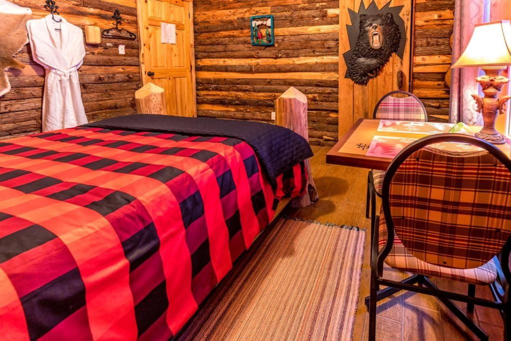 Une pièce confortable avec un lit, une chaise, une table et une décoration représentant une tête d’ours accrochée au mur.