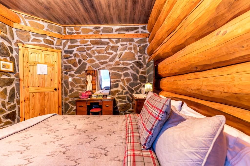 A room with a stone wall, wooden door, and a bed with a plaid blanket.