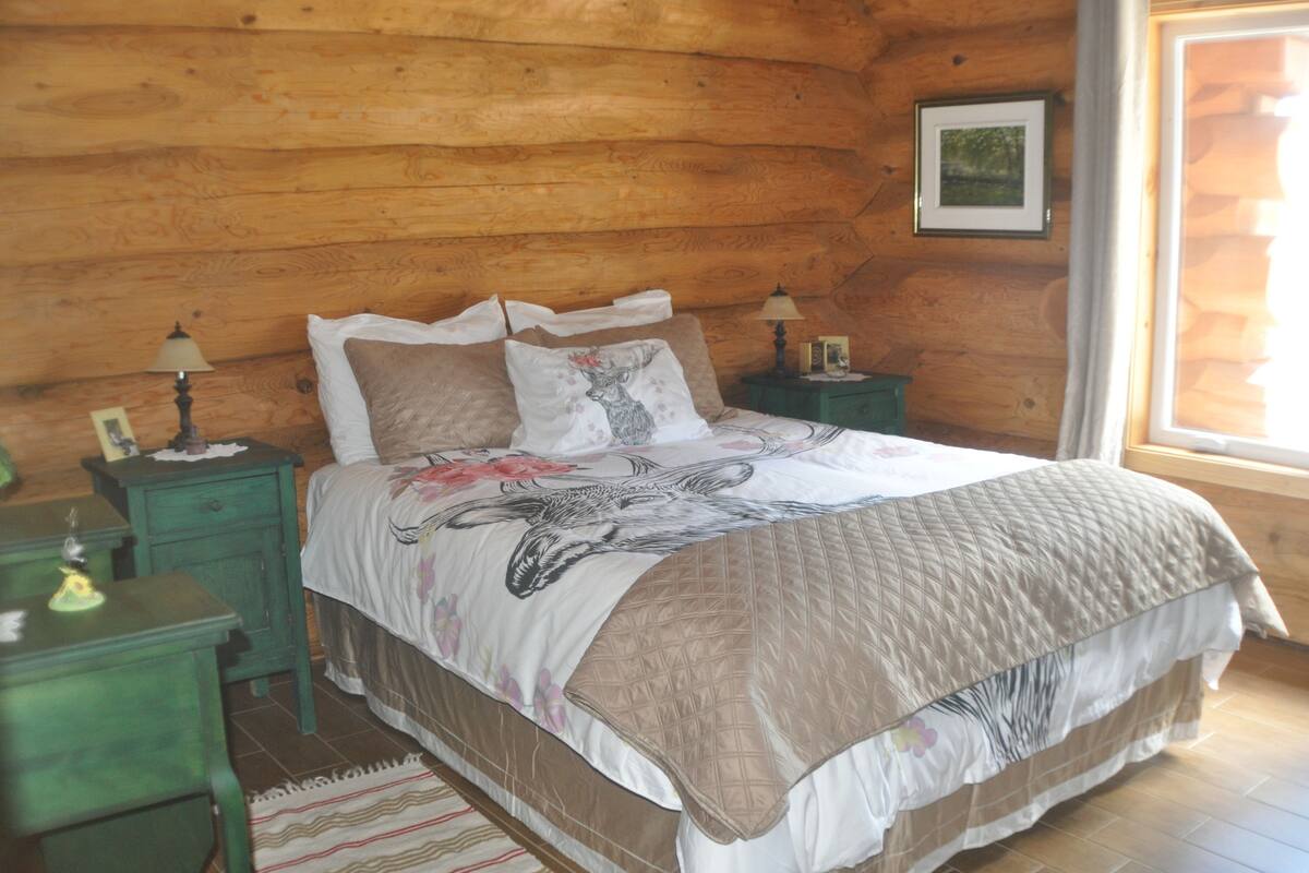 A wooden-paneled bedroom with a bed, two bedside tables, and a window.