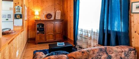 Un intérieur en bois avec un canapé, un meuble et une fenêtre avec des rideaux.