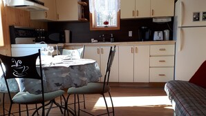 A cozy kitchen with wooden cabinets, a dining table with chairs, and a sofa. - Au domaine de La Giroux-ette (La Patrie)