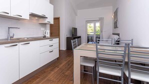 A modern kitchen with white cabinets, a wooden countertop, and a dining area with a glass table and metal chairs.