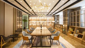Uma sala de conferências ampla, com uma mesa comprida, cadeiras modernas e um lustre único.