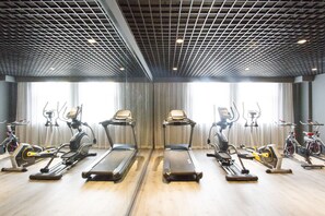 Ein Fitnessraum mit Laufbändern, Ergometer und Crosstrainern, die in Reihen angeordnet sind.