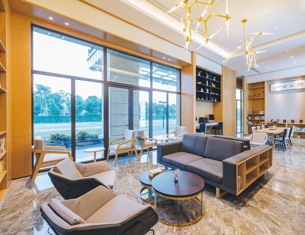 A spacious, modern lounge area with comfortable seating, a coffee station, and a view of the outdoors.