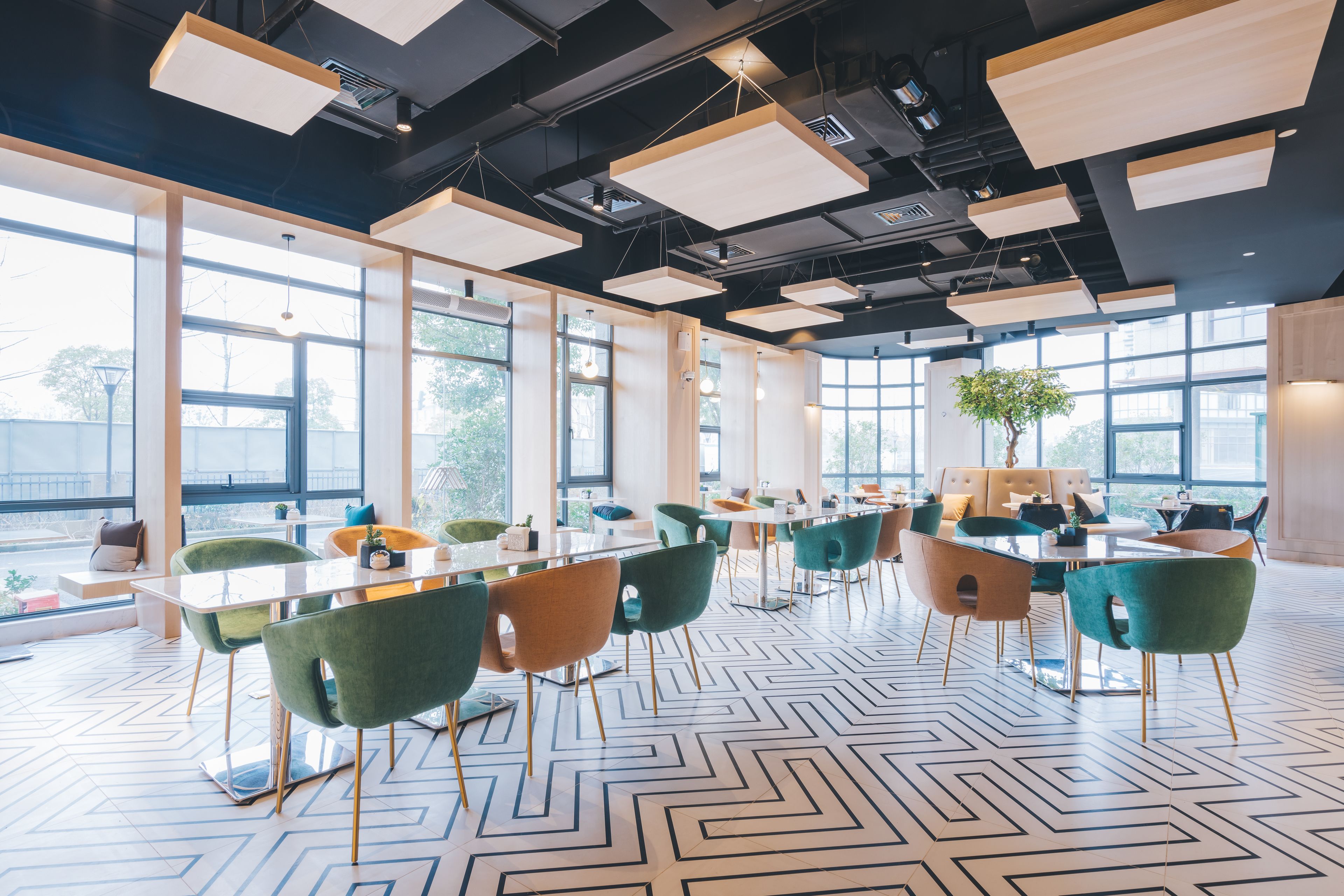 Een moderne congreszaal met grote ramen, een vloer met een geometrisch patroon en modern meubilair.