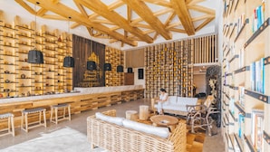 Ein modernes Interieur mit Holzbalken, Bücher- und Flaschenregalen, Korbmöbeln und einer Marmorplatte.