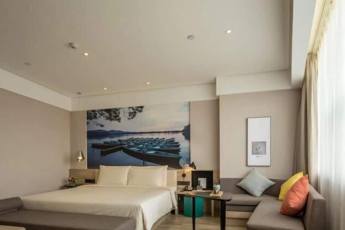 Ein Hotelzimmer mit einem großen Bett, einer Couch, einem kleinen Tisch und einem Bild von Booten an der Wand.