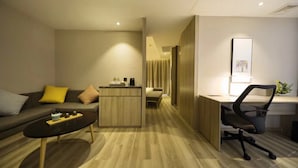 A modern hotel room with a sofa, a desk, and a small kitchenette. - Atour Hotel People's Square Xiaoshan Hangzhou (Hangzhou)