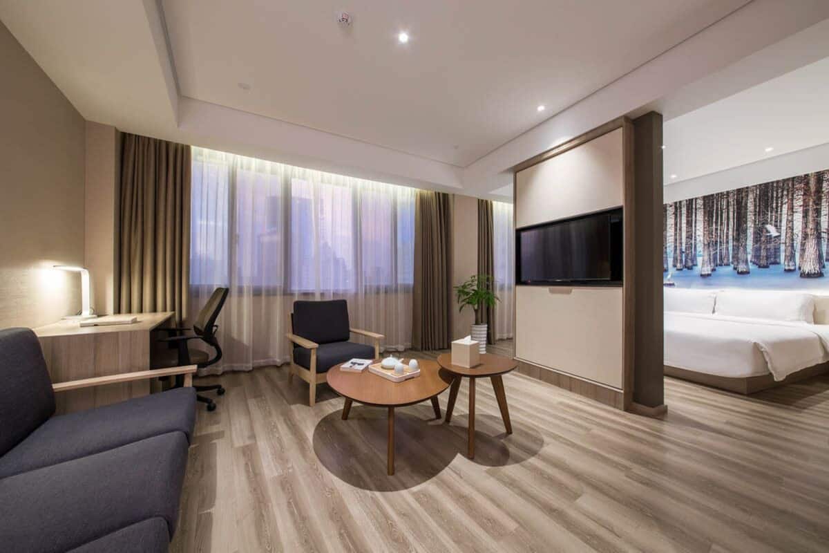 Una habitación de hotel moderna con sofá, escritorio, una mesa redonda, televisor y cama.