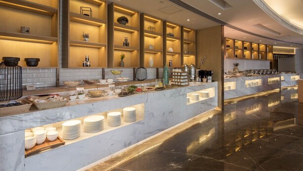 A modern hotel lobby with a marble reception desk, shelves with decorative items, and a polished floor. - Atour Hotel Tianyi Square Ningbo (Ningbo)