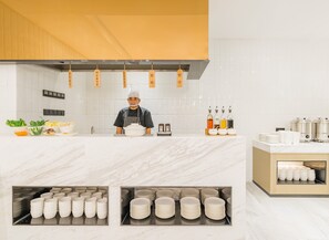 A modern kitchen with a chef, fresh produce, and neatly arranged plates and condiments. - Atour Hotel Mogan Mountain Deqing Huzhou (Huzhou)