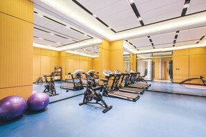 A gym with exercise equipment, large mirrors, and a blue floor.