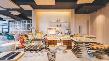 A buffet setup with various food items, a decorative figure, and a modern interior design.