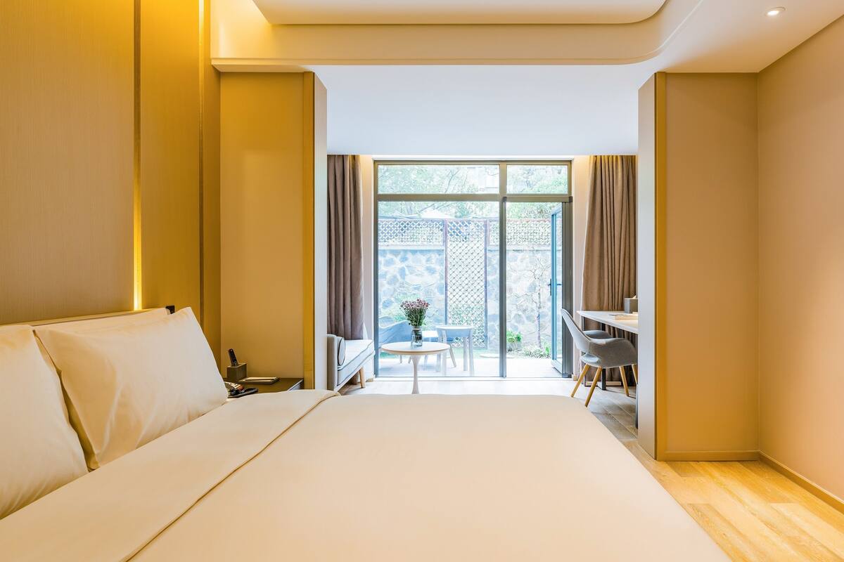 A hotel room with a large bed, a desk, and a view of the outside.