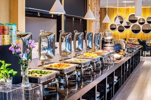 Un buffet proposant une variété de plats, présentés dans des récipients en verre transparent et disposés sur différents comptoirs, le tout dans un décor intérieur moderne.