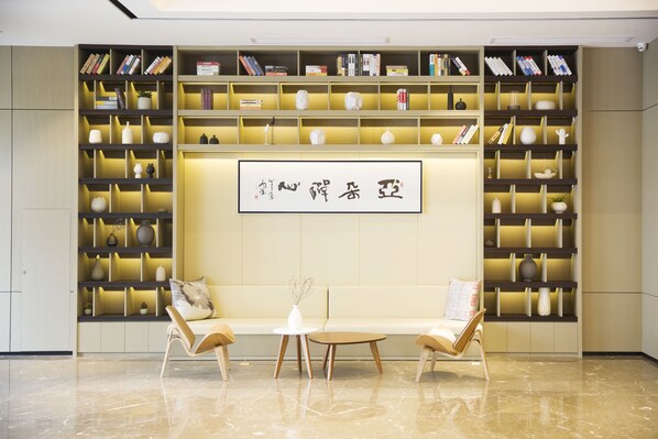 Une bibliothèque moderne avec des étagères, une table centrale et deux chaises.