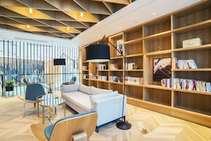 A modern library with a sofa, chairs, and bookshelves.